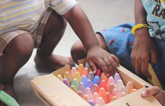 children reaching in a box for chalk