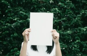 girl holding paper over her face