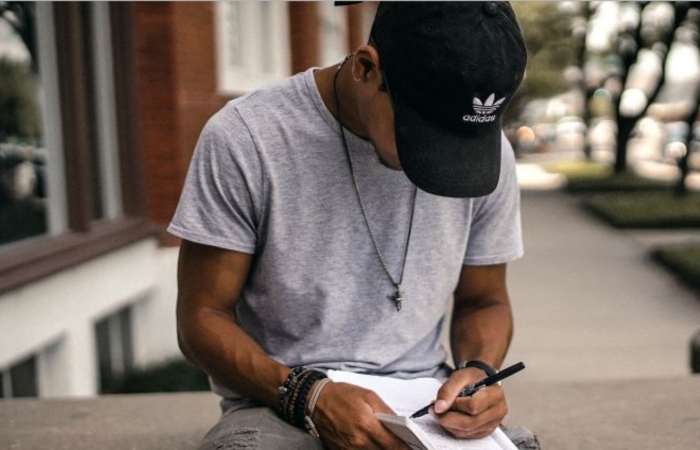 man writing in a journal outside