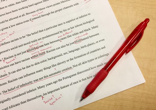 Red pen making corrections on paper