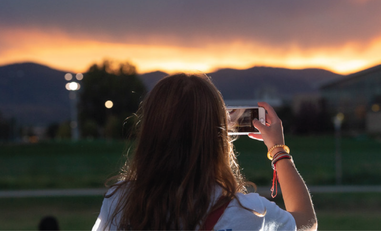 student taking a picture of the sunset