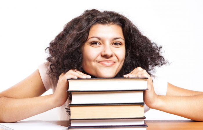 woman resting chin on a stack of books