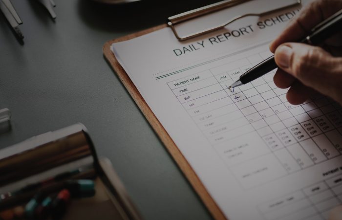person filling out daily report schedule with black pen