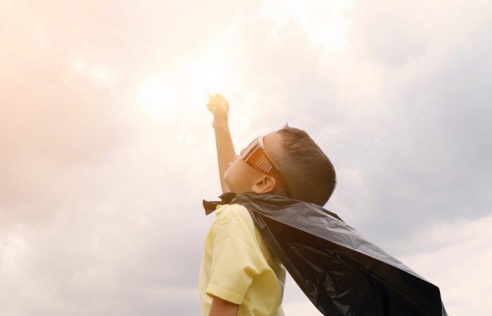 child in a cape doing superhero pose