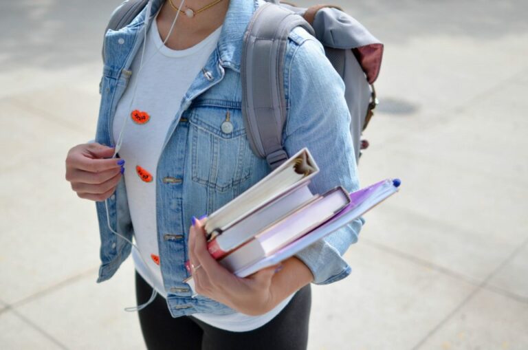 Woman in a backpack holding books
