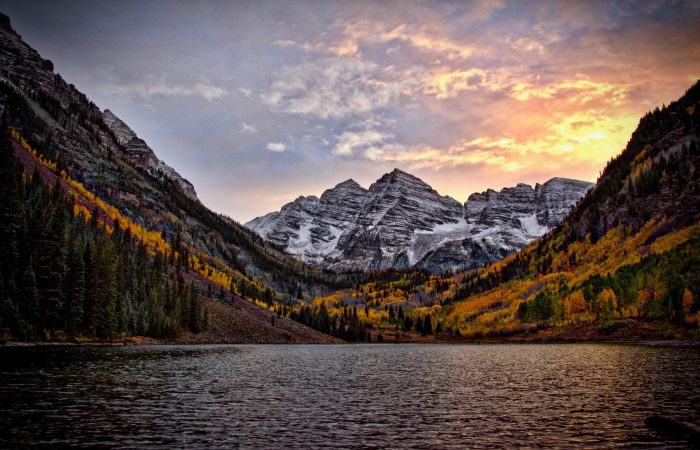 Maroon Bells mountain range behind fall landscape and alpine lake at sunset
