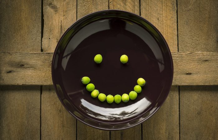 black plate with green peas in the shape of a smile